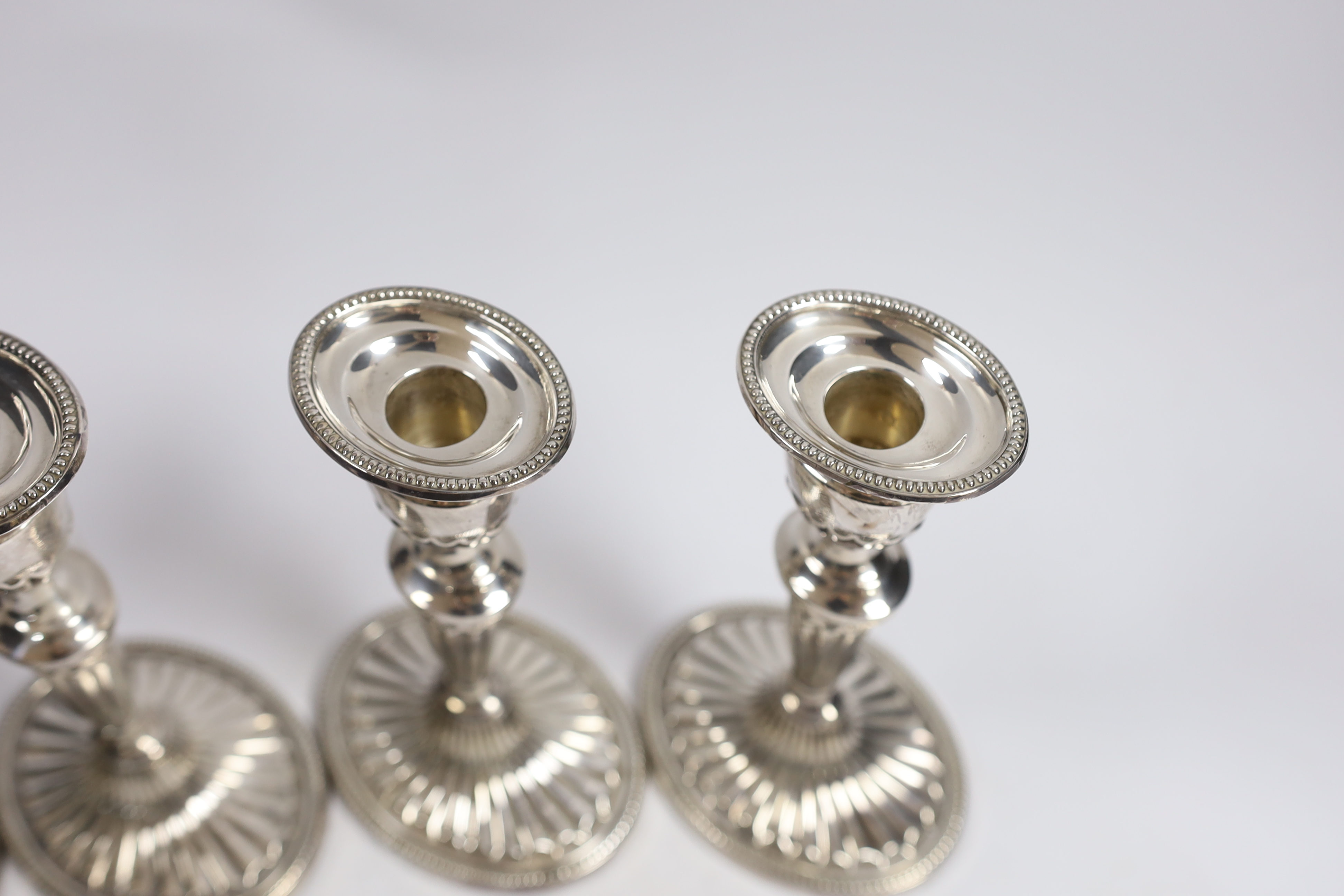 A set of four Elizabeth II silver candlesticks, with fluted stems and bases, C.J. Vander Ltd, London, 1973, 17.2cm, weighted.